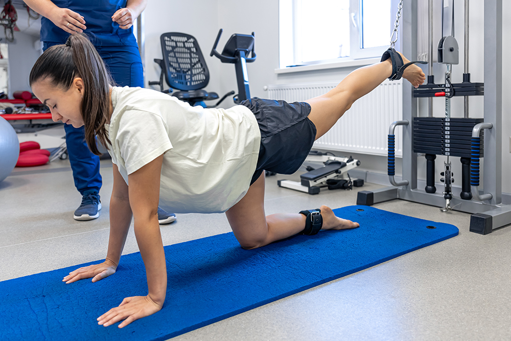 Woman Does Legs Raise Exercise, Therapist Helping With Mechanical Disorders. Woman Does Legs Raise Exercise, Therapist Helping With Mechanical Disorders.